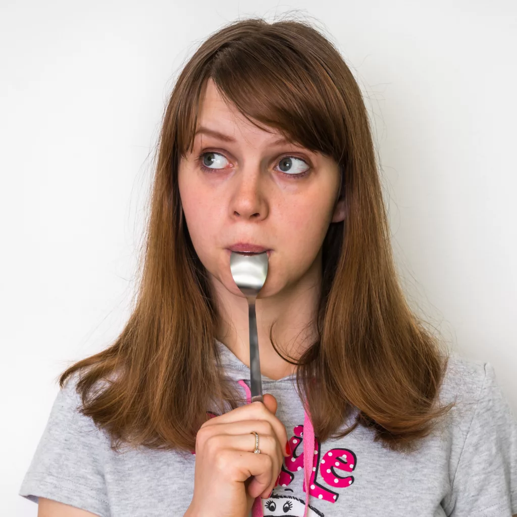 Woman eating a teaspoon of honey