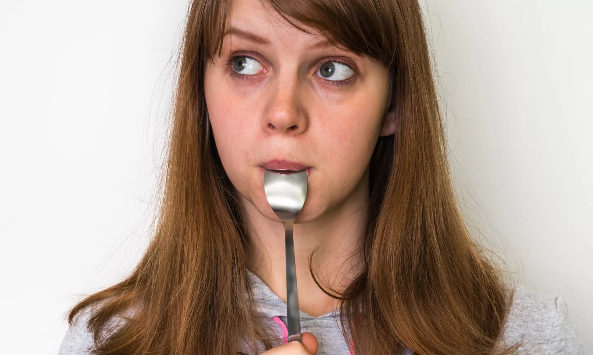 Woman eating a teaspoon of honey