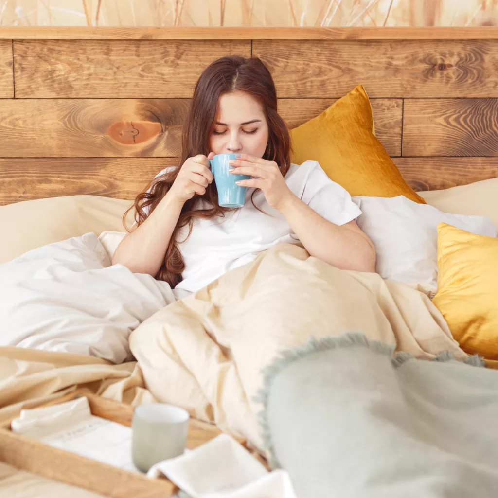 Woman drinking a hot drink in bed